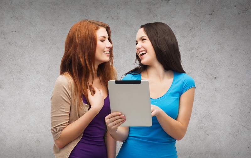 8959449-two-smiling-teenagers-with-tablet-pc-computer